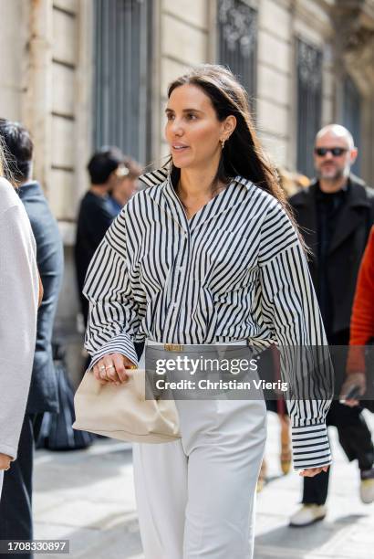 Guest wears black white striped button shirt, white Hermes belt, pants during the Womenswear Spring/Summer 2024 as part of Paris Fashion Week on...