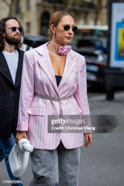 Guest wears pink belted striped blazer, white bag, grey denim jeans during the Womenswear Spring/Summer 2024 as part of Paris Fashion Week on...