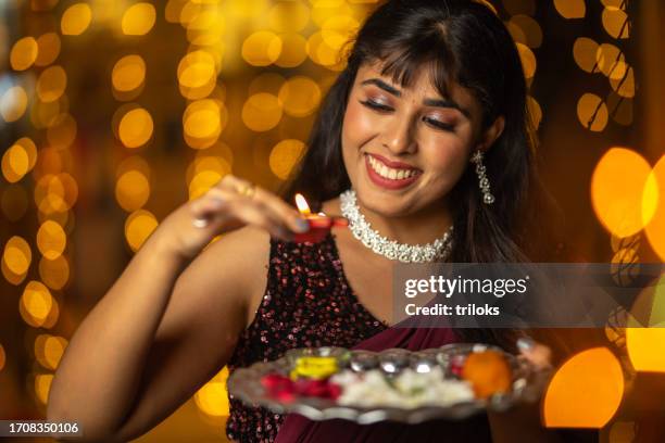 woman with diya and plate in illuminated home during festival - the dussehra vijaya dashami festival stock pictures, royalty-free photos & images