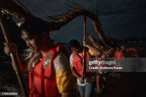 Members of the fire dragon dance team bring the dragon to the sea as part of the ending ceremony on September 29, 2023 in Hong Kong, China. Fire...