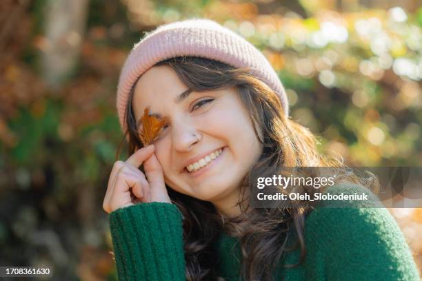 ritratto di donna che copre il suo occhio con la foglia autunnale - woman face hat foto e immagini stock