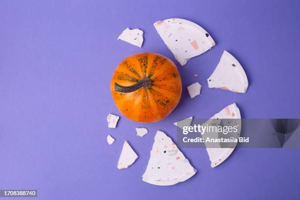 top view of jack be little pumpkin on purple background with cracked plate around. - jack be little squash ストックフォトと画像
