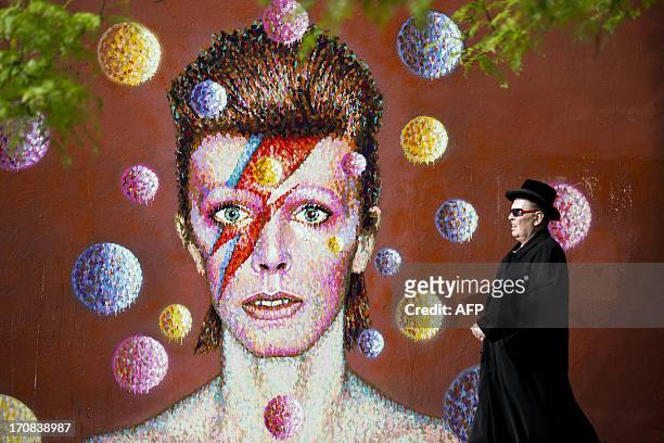 Man walks past a 3D wall portrait of British musician David Bowie, created by Australian street artist James Cochran, also known as Jimmy C, in...
