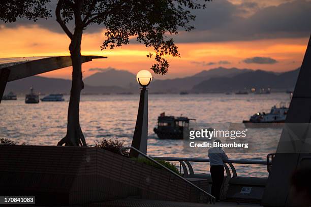Man stands by the waterfront at sunset in Hong Kong, China, on Tuesday, June 18, 2013. A shortage of housing, low mortgage costs and a buying spree...