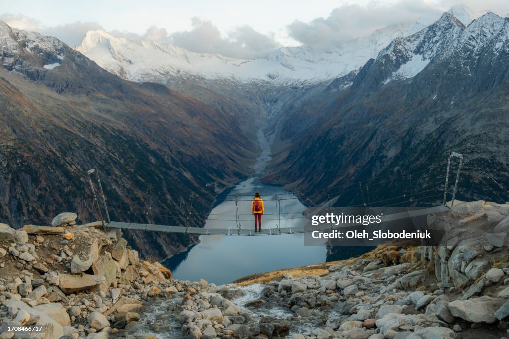 Frau auf der Brücke auf dem Hintergrund des Sees in den österreichischen Alpen