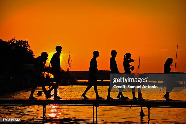 Sunset silhouette of college students on Lake Mendota at the Student Memorial Union Terrace at the University of Wisconsin-Madison. Madison,...