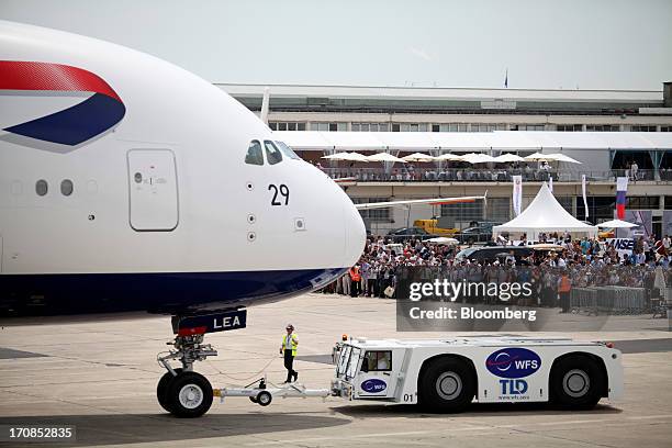 Visitors watch as an aircraft tractor pulls an Airbus SAS A380 aircraft, operated by British Airways, on the second day of the Paris Air Show in...