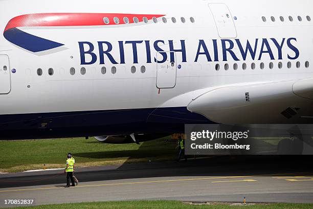 Ground crew stand beneath the fuselage of an Airbus SAS A380 aircraft, operated by British Airways, on the second day of the Paris Air Show in Paris,...