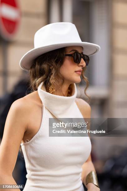 Guest is seen wearing a white hat, brown sunglasses, a gold bracelet and a sleeveless white turtle neck top outside Victoria Beckham show during the...