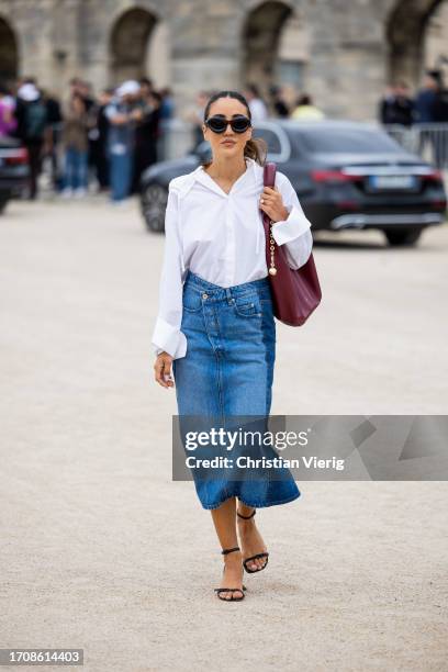 Tamara Kalinic wears denim skirt, white button shirt, burgundy bag outside Loewe during the Womenswear Spring/Summer 2024 as part of Paris Fashion...