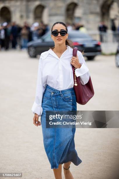 Tamara Kalinic wears denim skirt, white button shirt, burgundy bag outside Loewe during the Womenswear Spring/Summer 2024 as part of Paris Fashion...