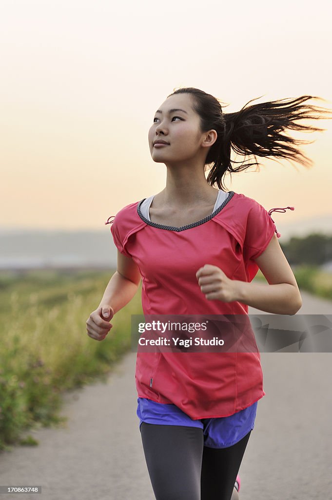 Woman running for exercise at sunset.