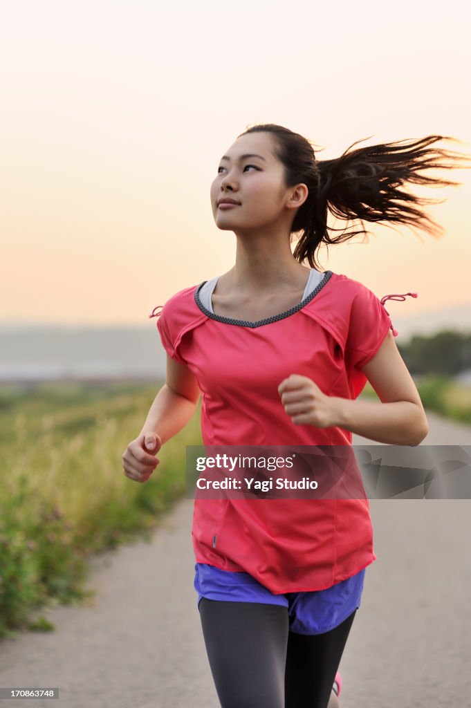 Woman running for exercise at sunset.