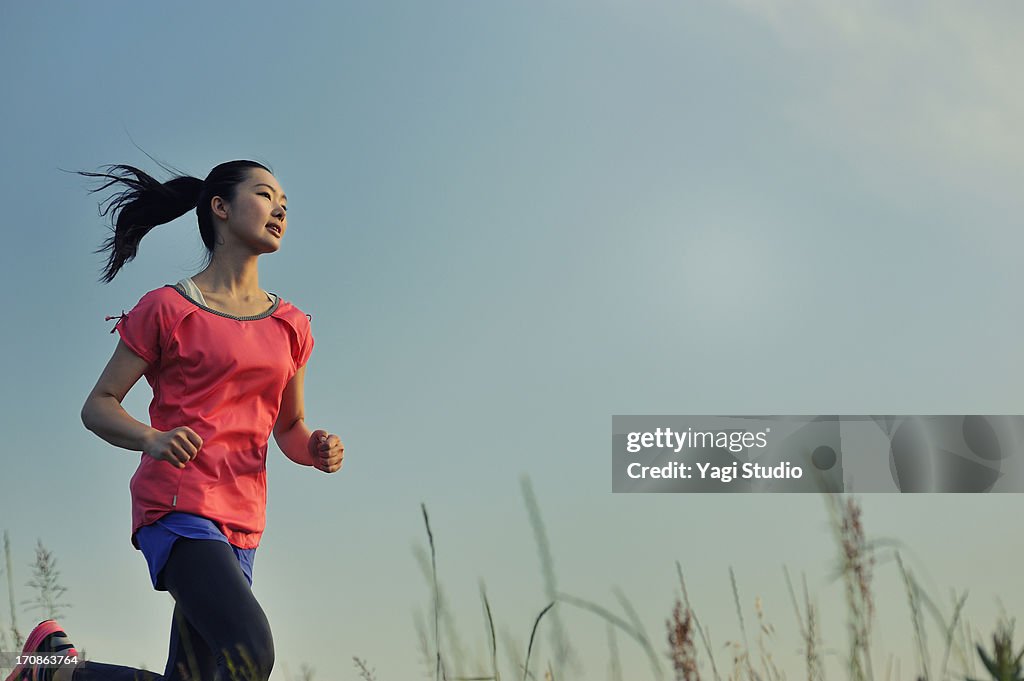 Woman running for exercise at sunset.