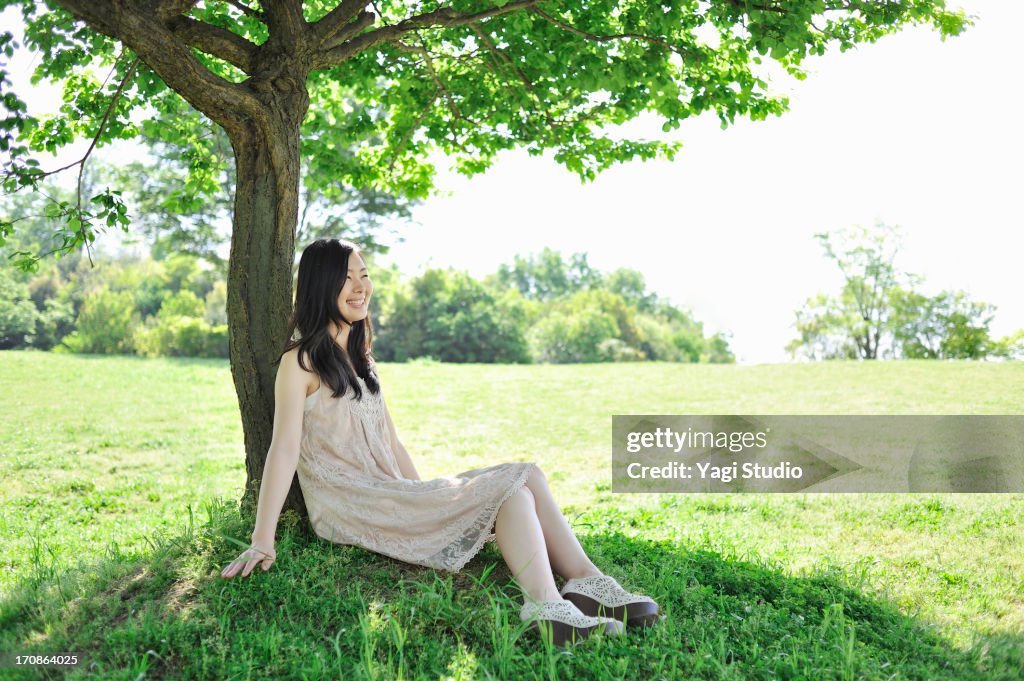Woman leaning on tree in nature.