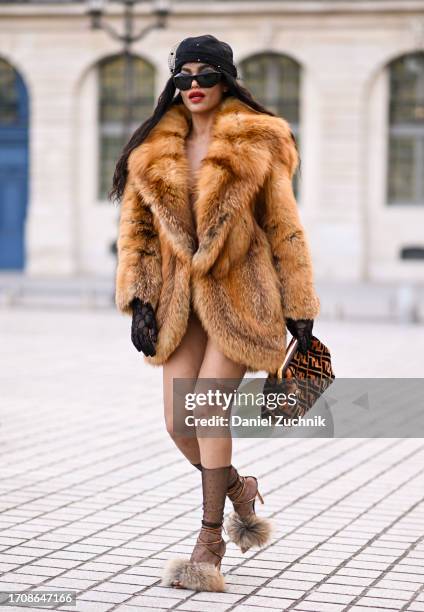Leila Depina is seen wearing a vintage fur coat, Fendi bag, Gucci sheer gloves, faux fur heels and a black cap with black sunglasses during the...