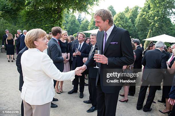 In this handout photo provided by the German Government Press Office , German Chancellor Angela Merkel shakes hands with NBA basketball player Dirk...
