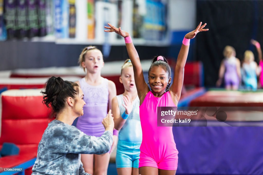 Gymnastics coach with girls practicing in gym