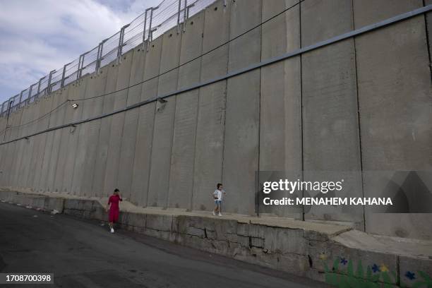 An Ultra-Orthodox Jewish pilgrim walks with her son next to the concrete wall protecting Rachel's Tomb, Judaism's third holiest shrine, located in...