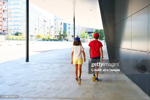 rear view of two boys in casual clothes walking on the sidewalk outside a building on the street. - pontevedra province ストックフォトと画像