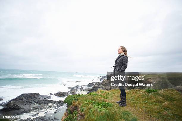 woman standing on coastline with eyes closed. - überzieher stock-fotos und bilder