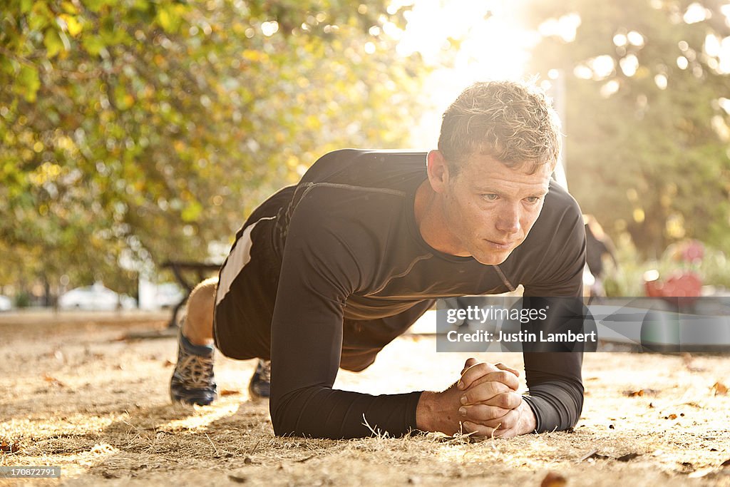 MAN EXERCISING IN PARK PERFORMING A PLANK