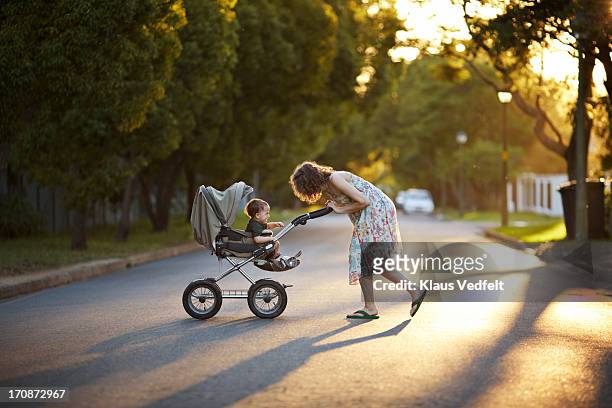 mother & son walking with stroller in the sunset - kinderwagen stockfoto's en -beelden