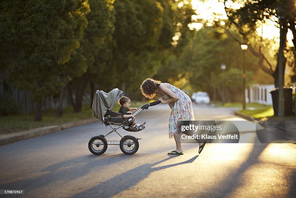 Mother & son walking with stroller in the sunset