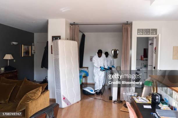 Pest control workers from Societe Mesnuisibles sprays insect killer solution onto a bed frame, inside an apartment containing bed bugs, in Paris,...