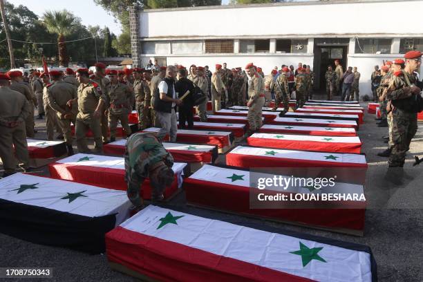 Syrian soldiers arrange caskets during the funeral of the victims of a drone attack targeting a Syrian military academy, outside a hospital in...