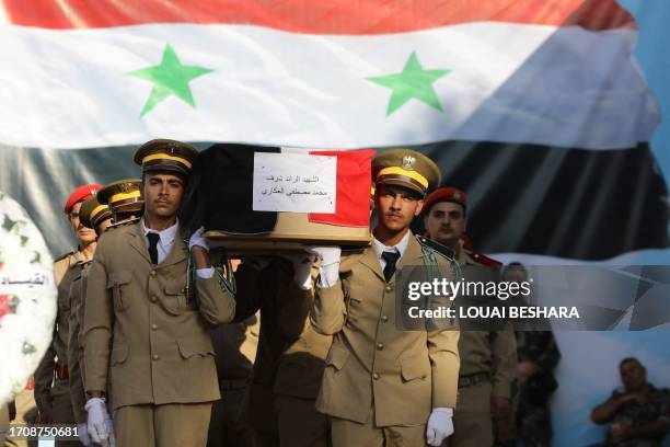 Syrian soldiers carry a casket during the funeral of the victims of a drone attack targeting a Syrian military academy, outside a hospital in...