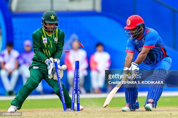 Afghanistan's Mohammad Shahzad is dismissed by Pakistan's Arafat Minhas during the 2022 Asian Games men's second semi-final cricket match between...