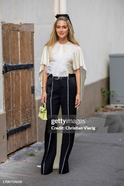 Emili Sindlev wears black white pants, creme white top with feathers, Hermes bag outside Victoria Beckham during the Womenswear Spring/Summer 2024 as...