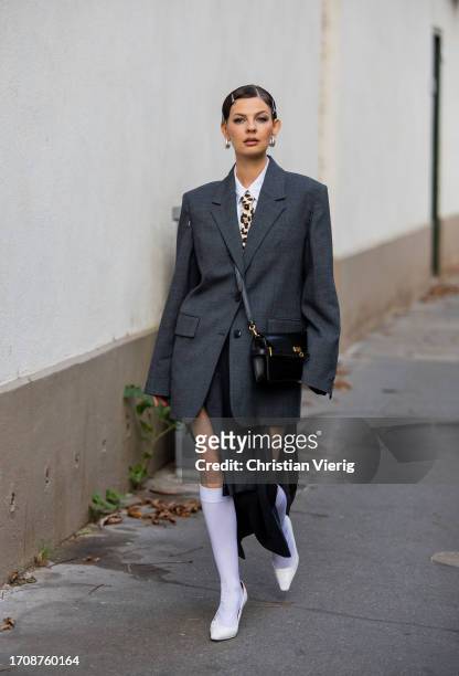 Guest wears grey oversized blazer, black bag outside Victoria Beckham during the Womenswear Spring/Summer 2024 as part of Paris Fashion Week on...