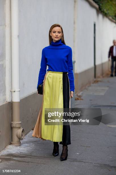 Victoria Magrath wears yellow black brown pleated high waisted skirt, blue turtleneck, Jimmy Choo bag outside Victoria Beckham during the Womenswear...