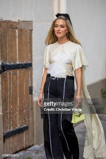 Emili Sindlev wears black white pants, creme white top with feathers, Hermes bag outside Victoria Beckham during the Womenswear Spring/Summer 2024 as...