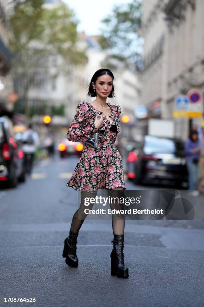 Heart Evangelista wears a headband, a cross necklace, a low neck mini dress with floral print, tights, platform leather boots, a silver bag, outside...