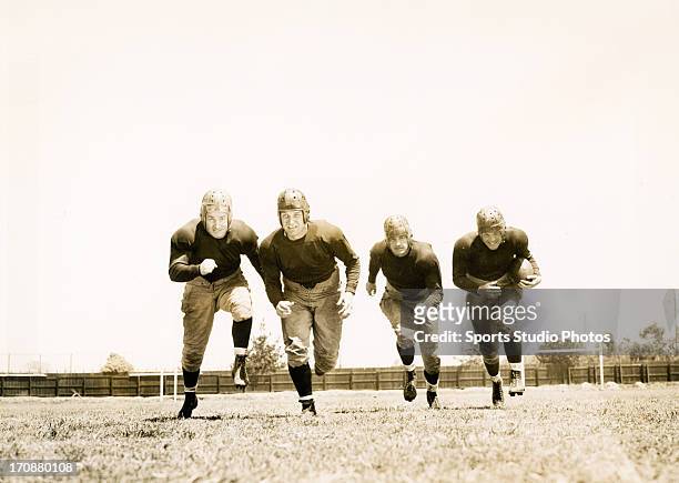 Actors Bill Byrne, Nick Lukats, Kane Richmond and Bill Marshall from the film "Knute Rockne, All American", running in formation towards the...