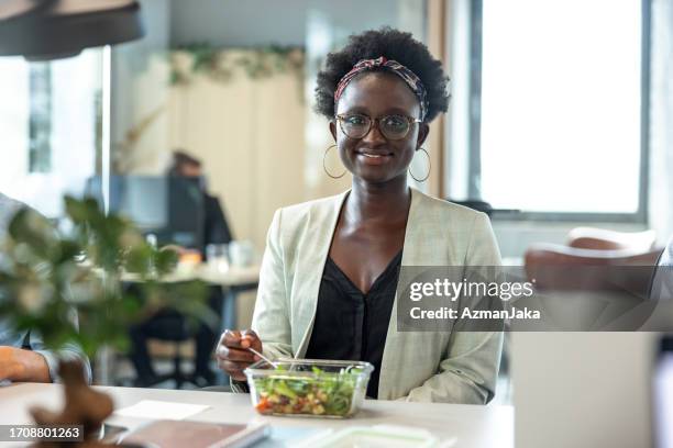 portrait of a beautiful dark-skinned young executive having a healthy lunch at the office - dark skin tone stock pictures, royalty-free photos & images