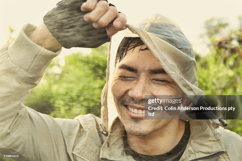Asian man wearing hood in rain
