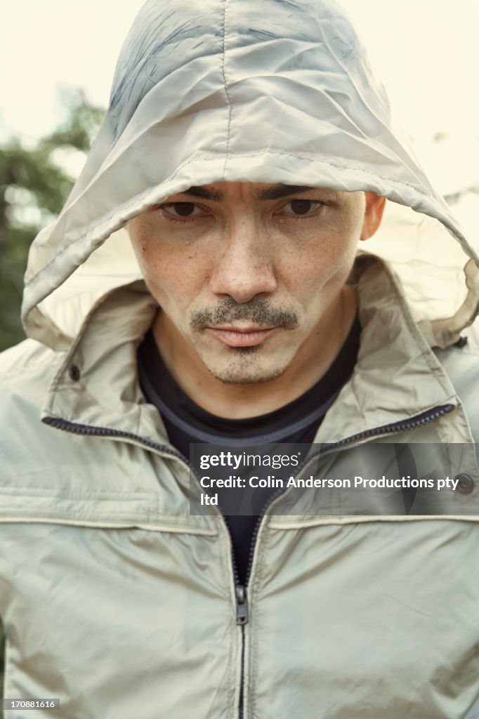 Asian man wearing hood outdoors