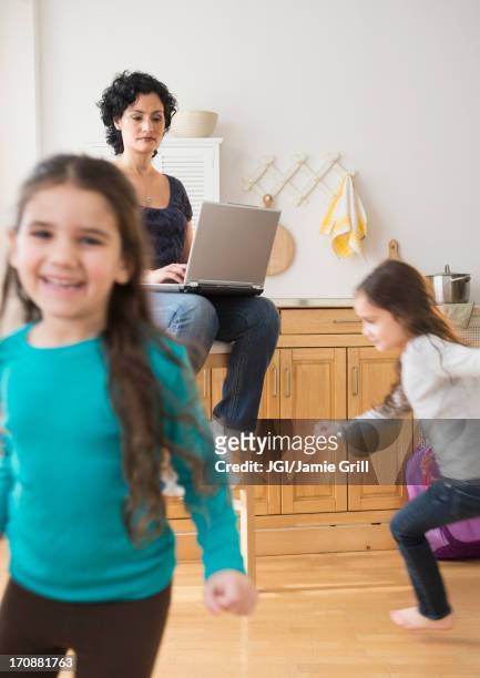 mother using laptop as daughters play - fast typing stock pictures, royalty-free photos & images