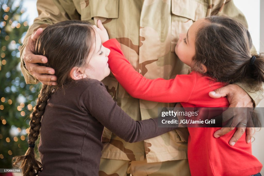 Daughters hugging soldier father