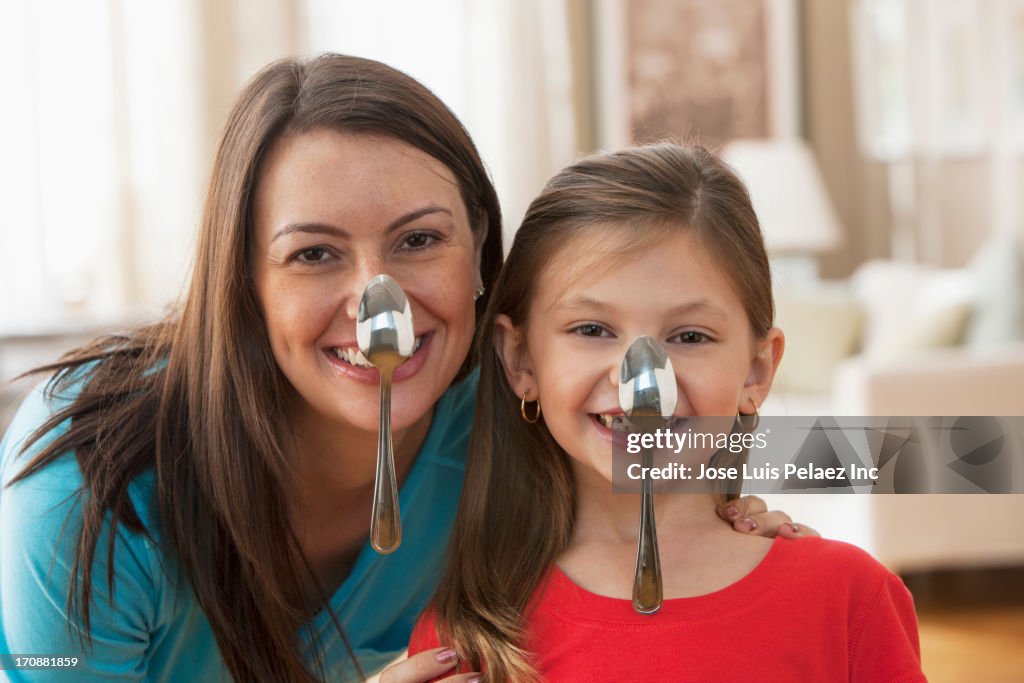 Caucasian mother and daughter balancing spoons on noses