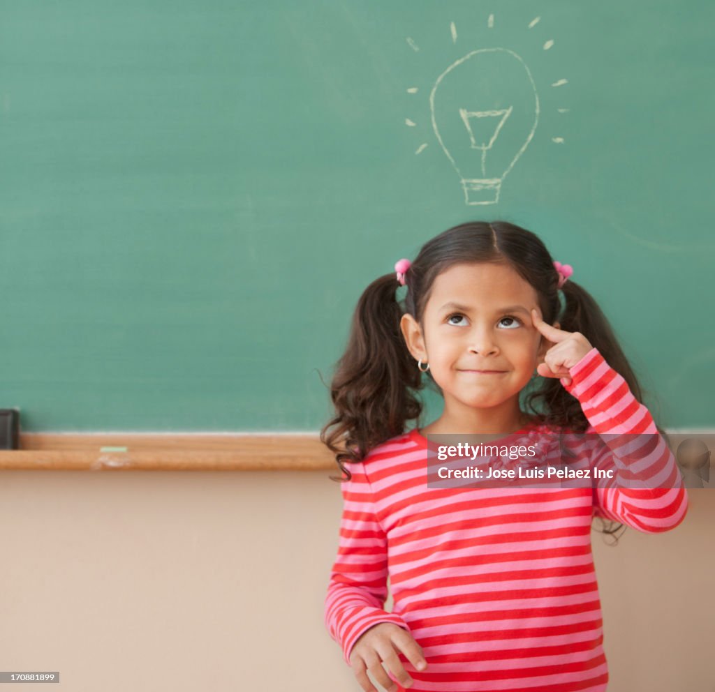 Hispanic girl at chalkboard with light bulb over head