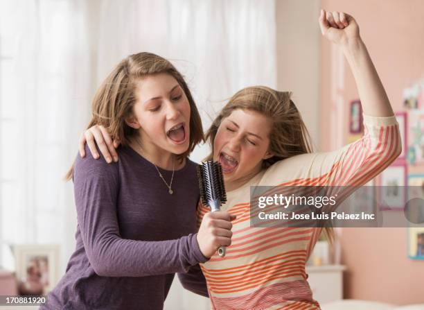 caucasian girls singing into hairbrush - due sorelle foto e immagini stock