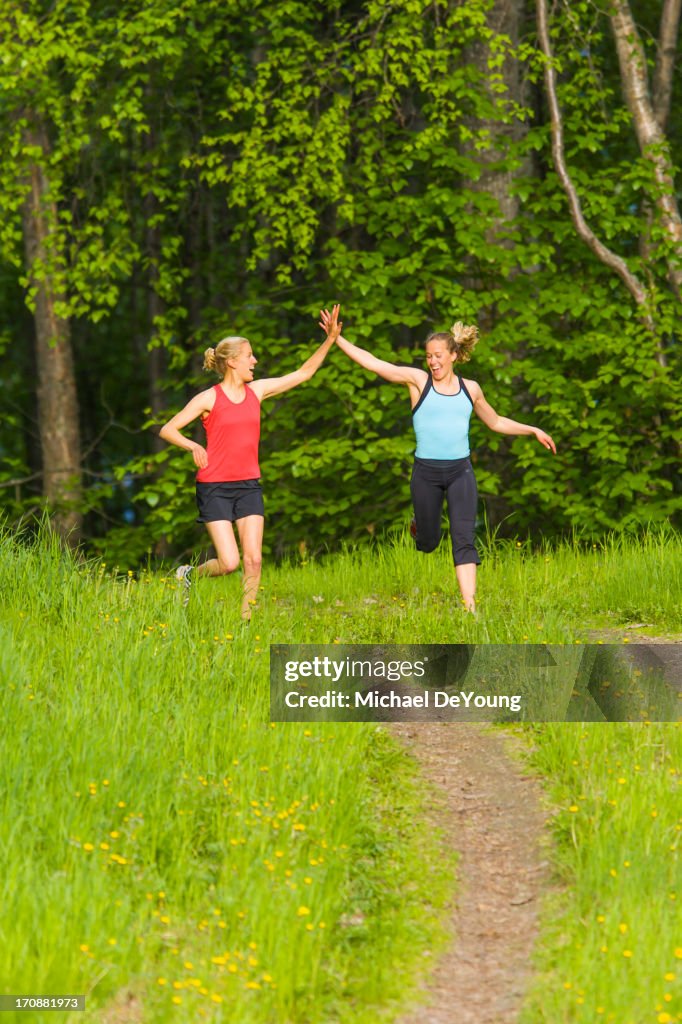 Caucasian runners high fiving on path