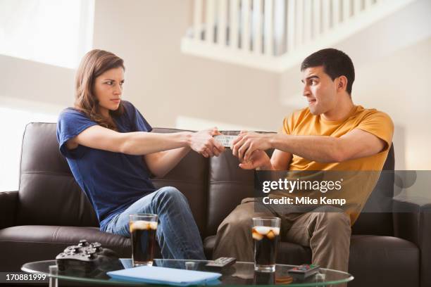 couple arguing over remote on sofa - tegendraads stockfoto's en -beelden