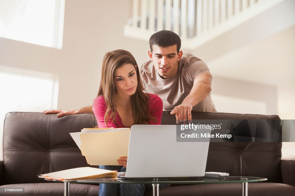 Couple reading papers at laptop together