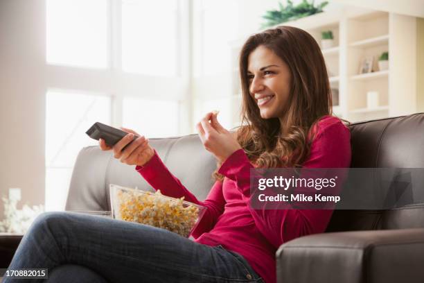 caucasian watching television on sofa - changing channels stockfoto's en -beelden